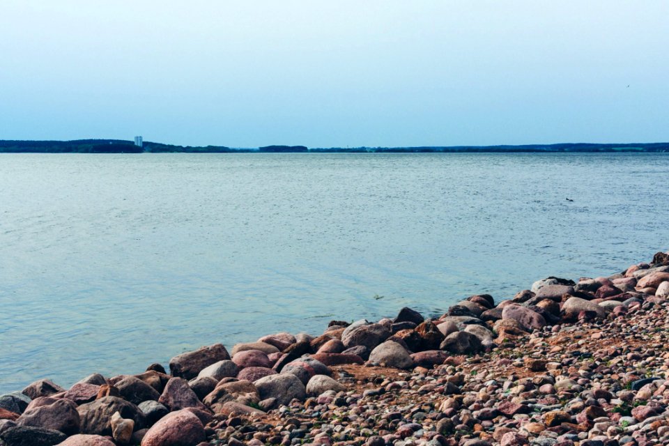 Rock Lot By The Body Of Water Under Blue Sky