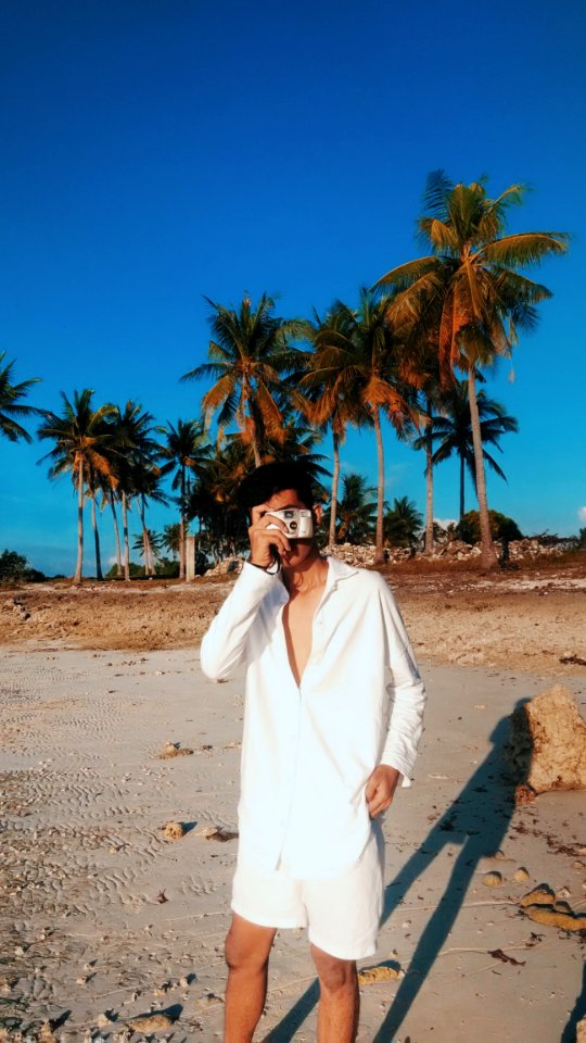 Man Wearing White Dress Shirt With White Shorts Holding Gray Camera