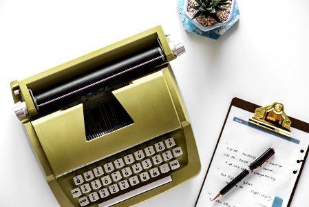 Gold Type Writer Beside Clip Board And Click Pen photo