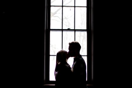 Man And Woman Kissing Beside Window photo