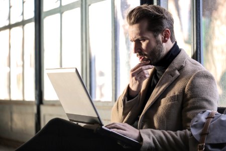 Man Wearing Brown Jacket And Using Grey Laptop photo