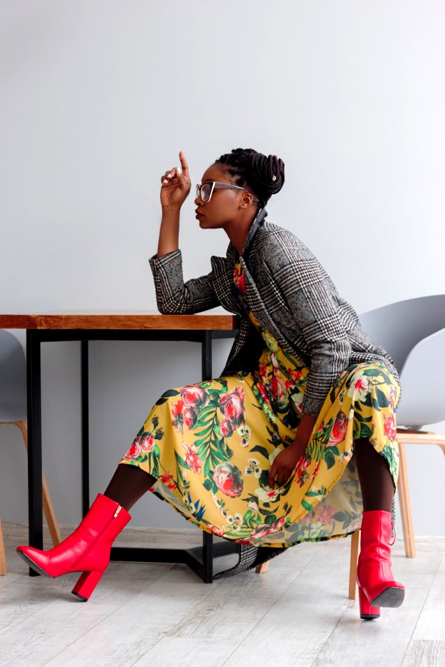Woman Sitting On A Chair With Open Legs And Right Hand On Top Of Wooden Table