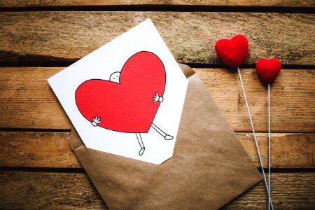 White Black And Red Person Carrying Heart Illustration In Brown Envelope photo