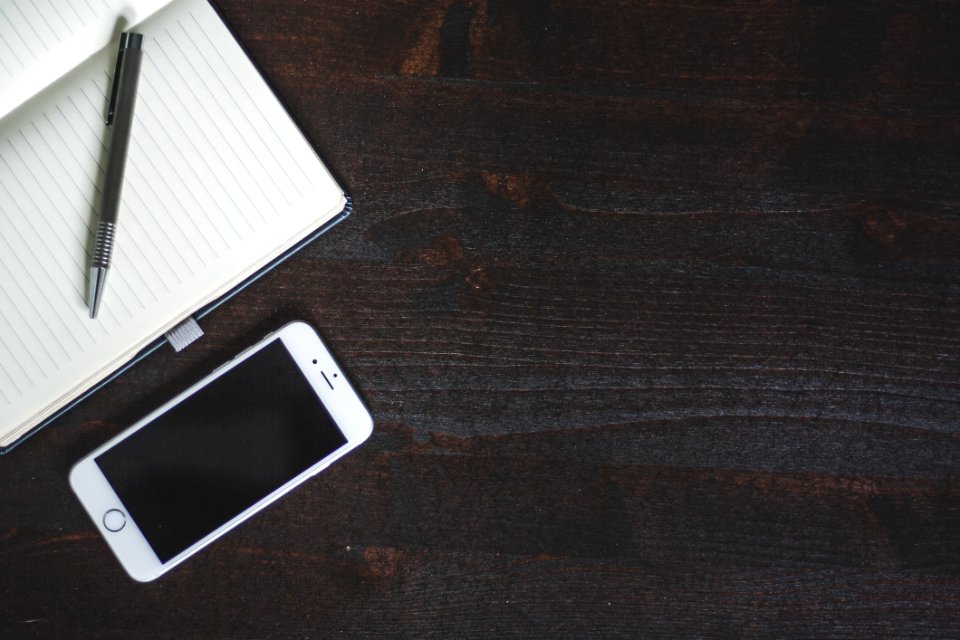 Silver Iphone 6 Beside White Book With Pen