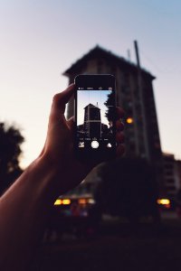 Person Holding Iphone Taking A Photo Of Building