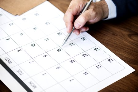 Person Pinpointing Pen On Calendar