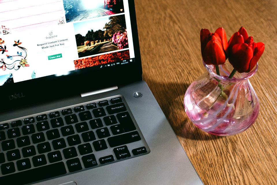 Black Dell Laptop Beside The Pink Glass Vase