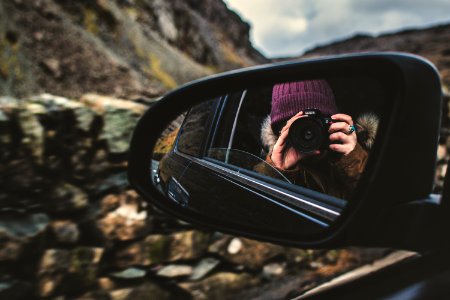Person Holding Dslr Camera Reflected On Black Framed Wing Mirror photo