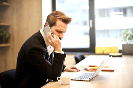 Man Having A Phone Call In-front Of A Laptop photo