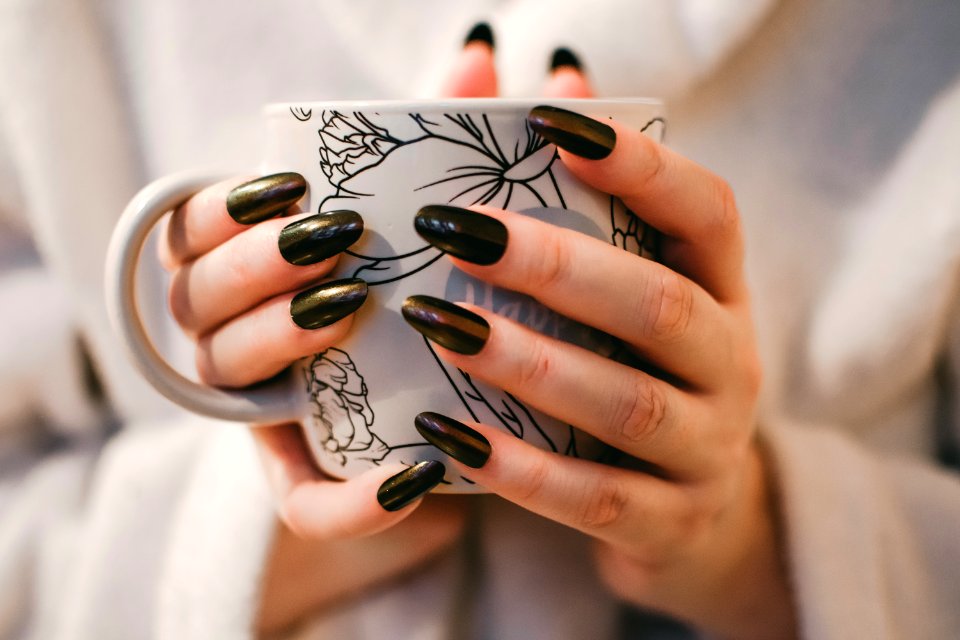 Woman With Black Manicure Holding White And Grey Floral Ceramic Cup photo