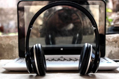 Photo Of Black Wireless Headphones In Front Of The Laptop photo