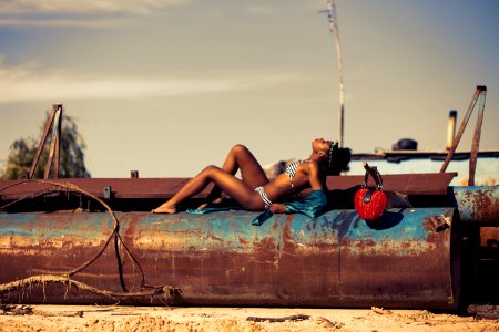 Woman In White And Blue Striped Two Piece Lying On Rustic Brown Metal Tank