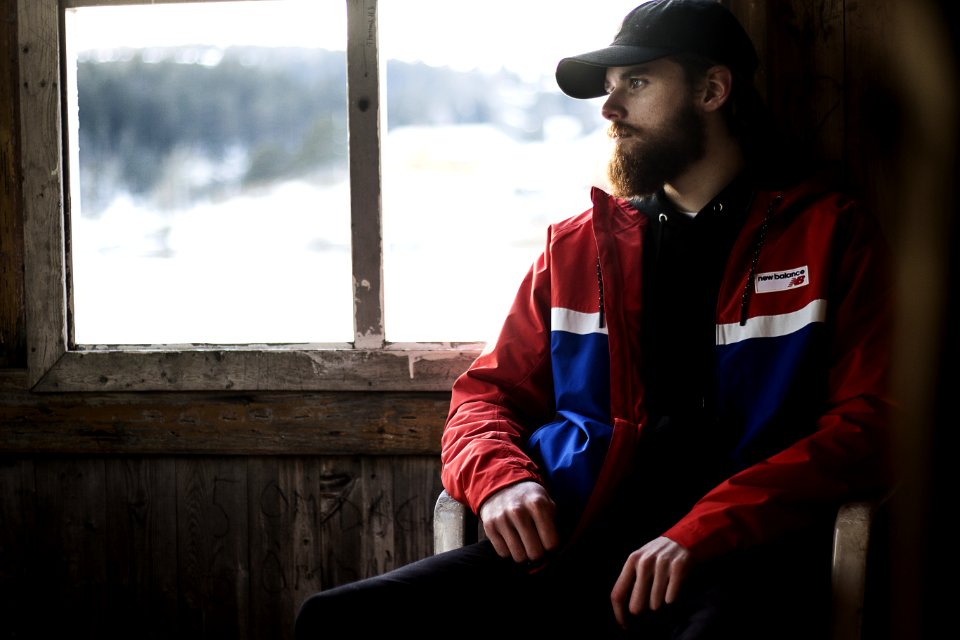 Photo Of Man Wearing Black Hat And Blue-and-red Jacket Near Window