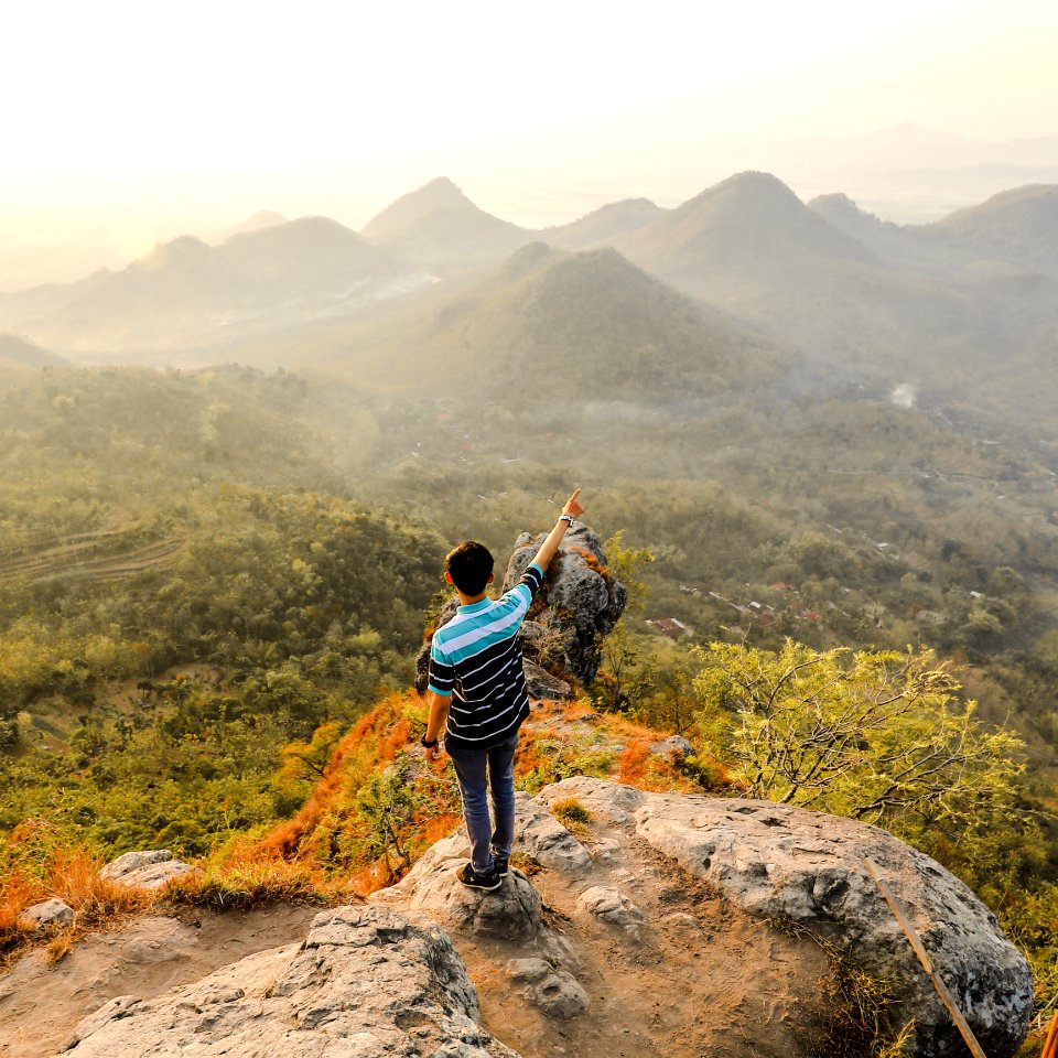 Photo Of Man Standing On Rock Mountain Pointing Out Mountain