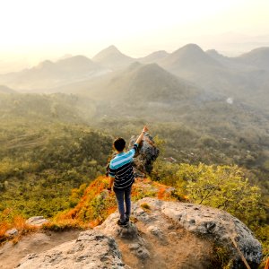Photo Of Man Standing On Rock Mountain Pointing Out Mountain