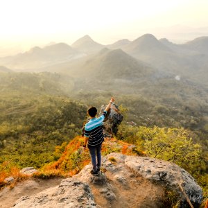 Photo Of Man Standing On Rock Mountain Pointing Out Mountain photo