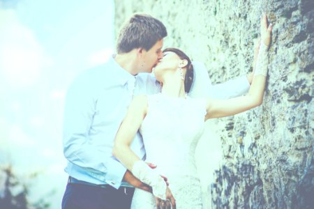 Man Kissing Woman Wearing Sleeveless Wedding Gown photo