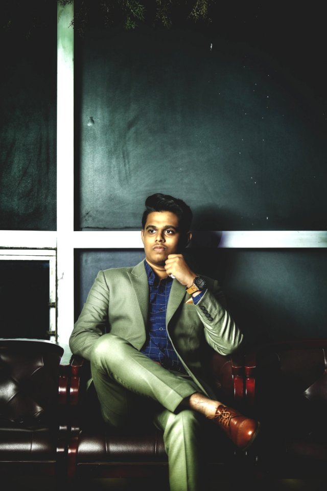 Man In Gray Notch-lapel Suit Jacket With Dress Pants While Sitting On Armchair photo