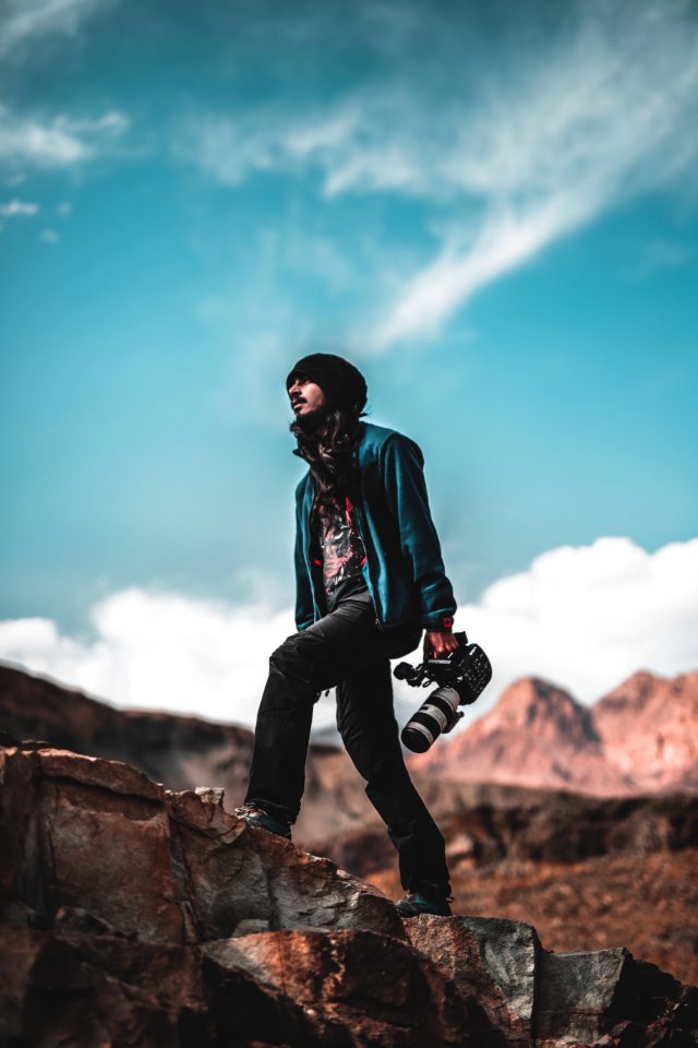 Man Wearing Blue Jacket Holding A White And Black Dslr Camera