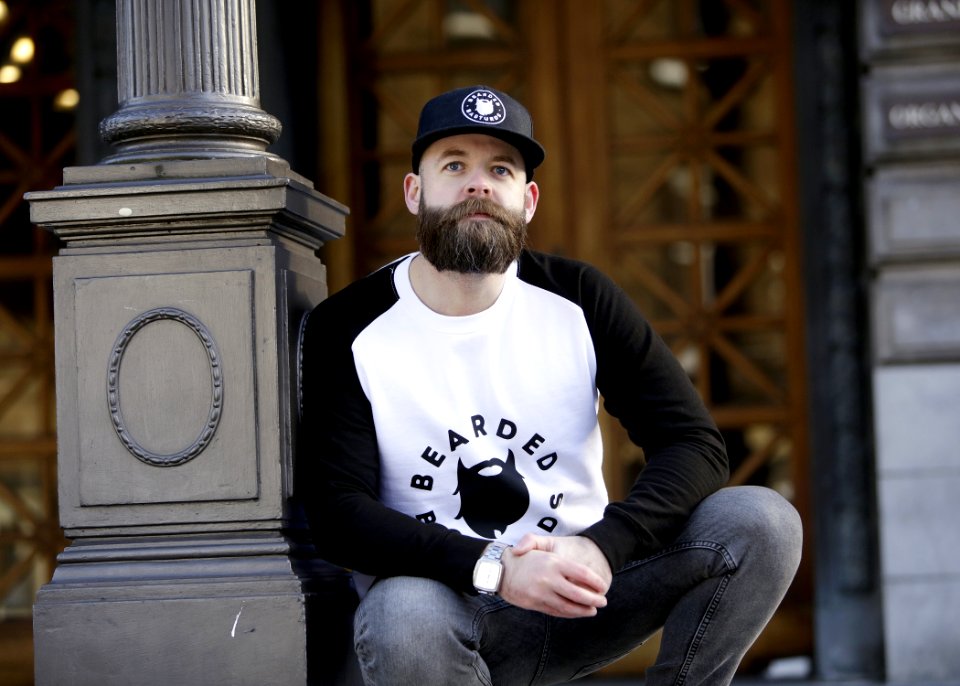 Man In White And Black Pullover Shirt Leaning On Black Post