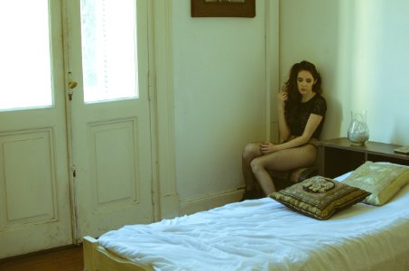 Woman Wearing Black Cap-sleeved Top Sitting On Chair Near Bed photo