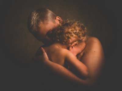 Photo Of Topless Person Carrying Curly Haired Child