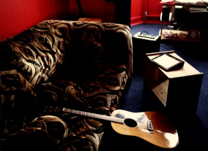 Brown Acoustic Guitar Leaning On Brown Velvet Couch photo