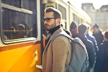 Man In Brown Coat And Gray Backpack Posing For A Photo photo