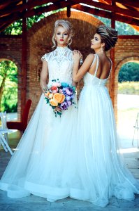 Woman In White Lace Wedding Dress Holding Flower Bouquet Beside Woman In White Dress