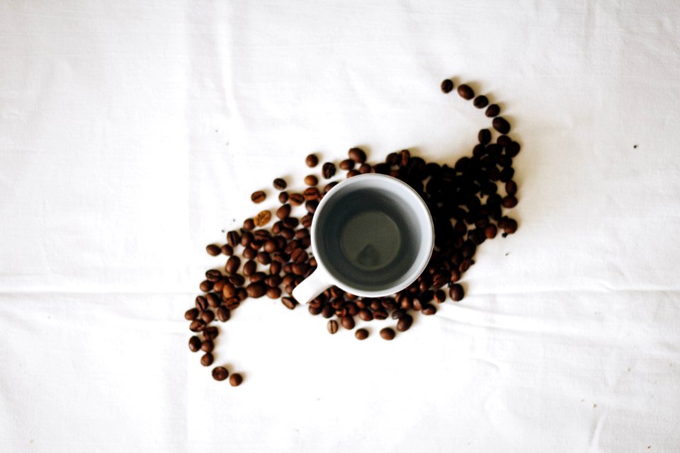 Empty White Ceramic Mug Surrounded By Coffee Grounds photo