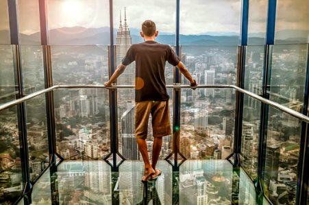 Man In Black T-shirt Looking Out Of Glass Windows During Sunset photo