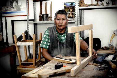 Man Wearing Green And White Stripe Shirt Holding Beige Wooden Frame On Table