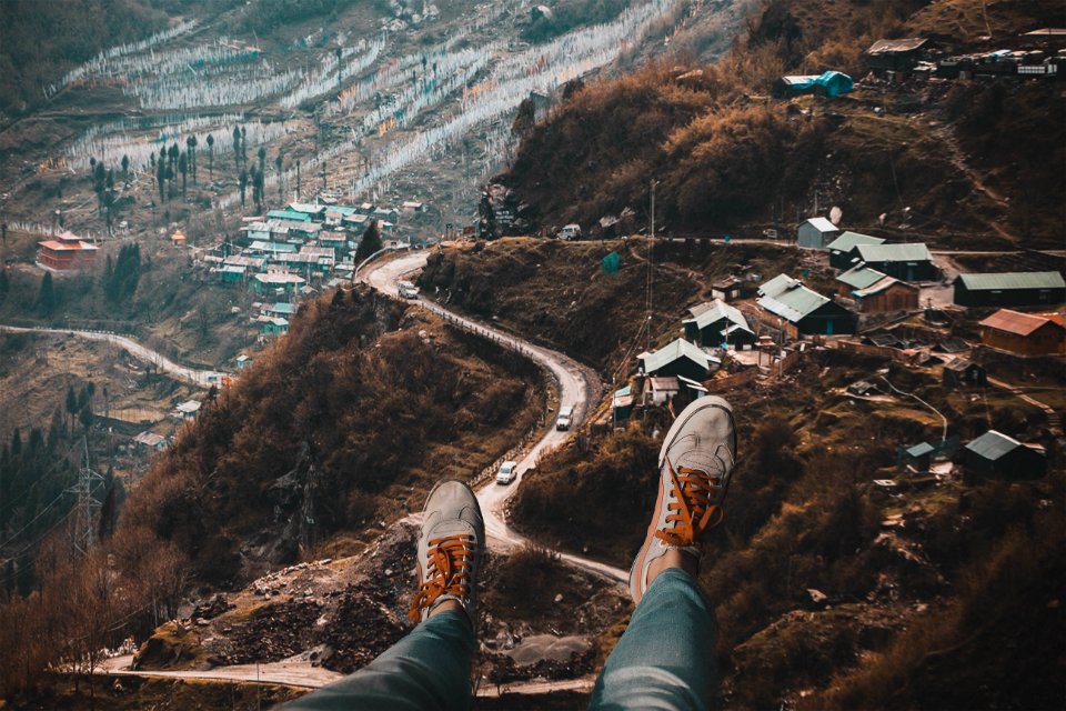 Person Wearing White Sneakers With Overlooking Of Village On Hills