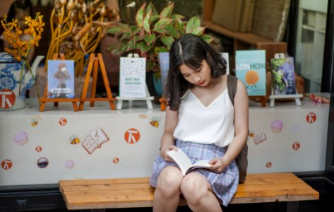 Woman Reading A Book While Sitting On A Bench photo