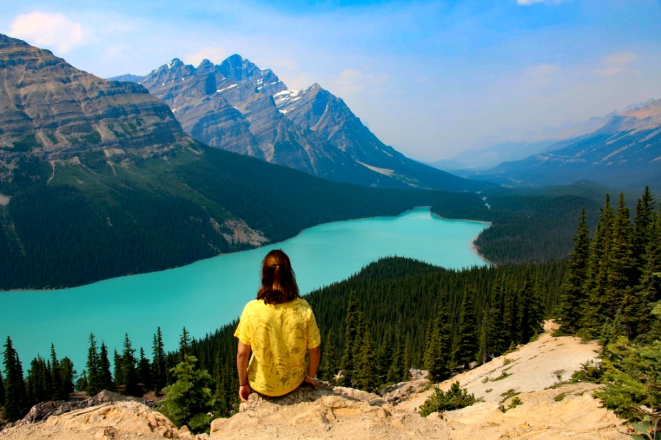 Person Sitting On Rocky Mountain Near Body Of Water