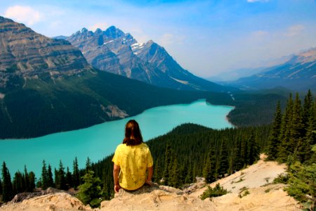 Person Sitting On Rocky Mountain Near Body Of Water photo