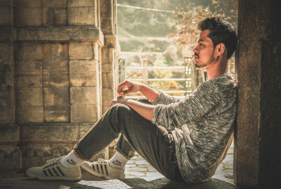 Photo Of Man Wearing Gray Sweater And Track Pants Leaning On Wall photo