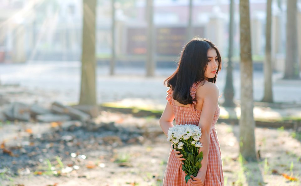 Woman Wearing Orange Sleeveless Dress Holding A Bouquet Of Flowers