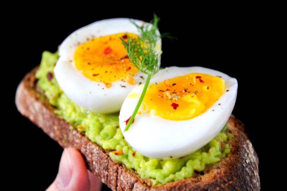 Sliced Egg On Top Of Green Salad With Bread
