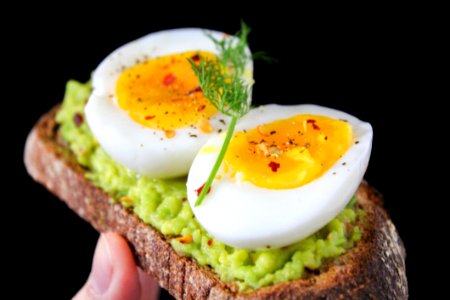 Sliced Egg On Top Of Green Salad With Bread