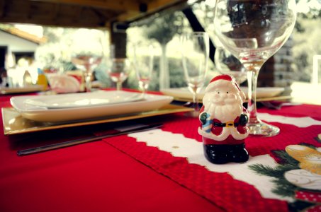 Santa Claus Ceramic Figurine Next To Wine Glasses And White Ceramic Plate photo