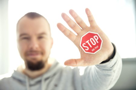 Photography Of A Persons Hand With Stop Signage photo