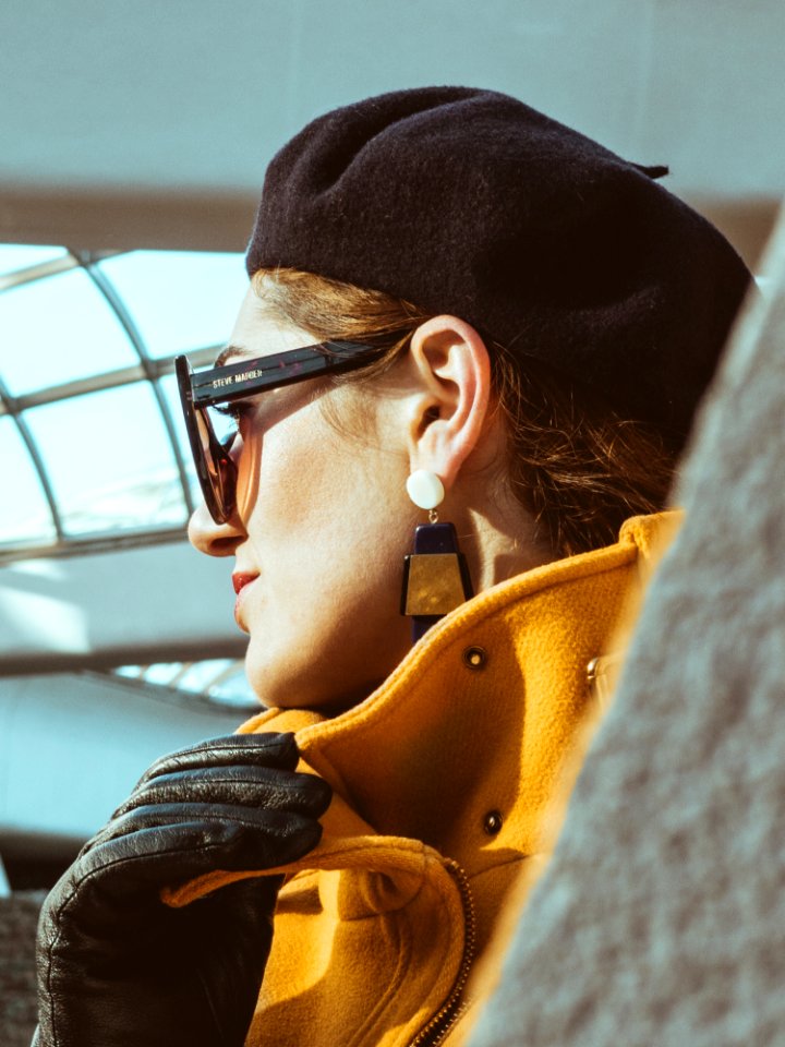 Woman In Yellow Trench Coat Black Leather Gloves Black Sunglasses And Black Hat