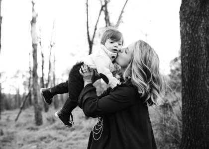 Grayscale Photo Of Woman Kissing Toddler On Cheek photo