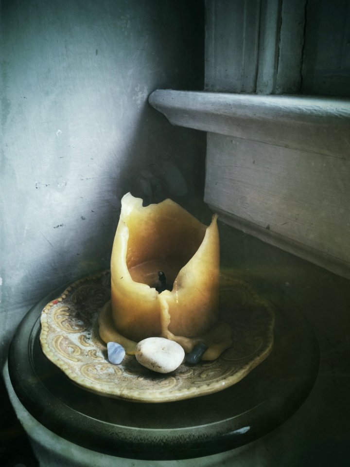 Beige Candle On Beige Saucer Plate Beside Polished Pebbles Near Window