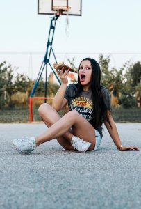 Girl Sitting On Basketball Field Holding Pizza