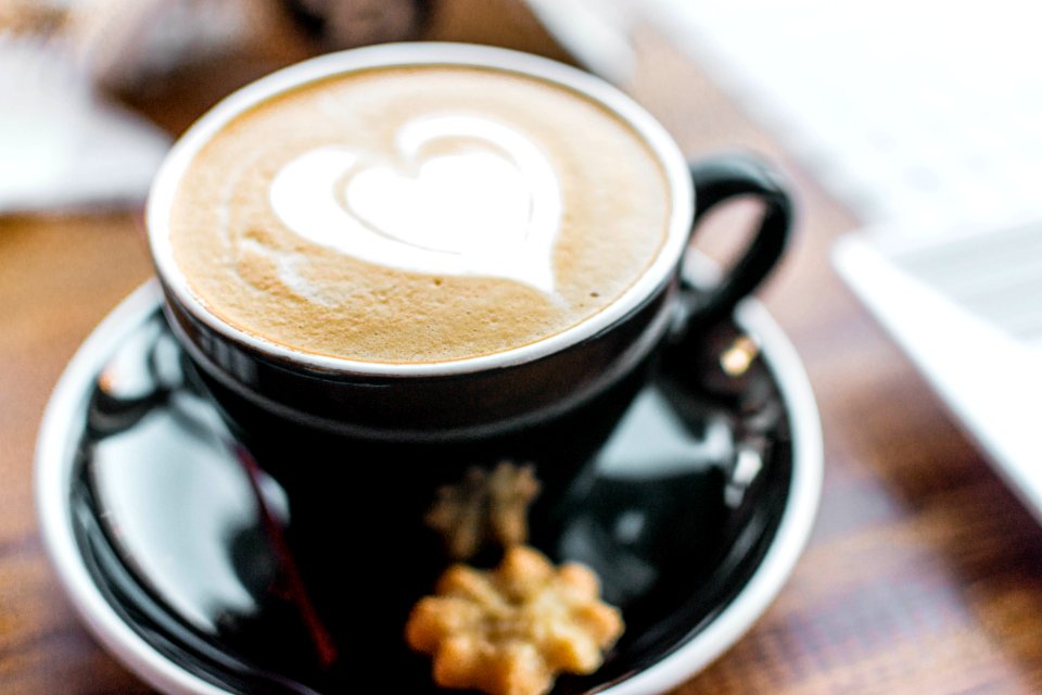 Black Ceramic Cup With Brown Liquid With Heart-shape On Black Ceramic Saucer photo