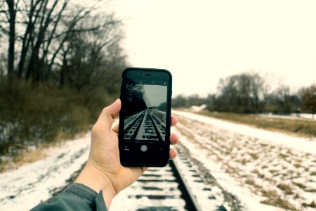 Person Holding Iphone Taking Photo Of Train Rails photo