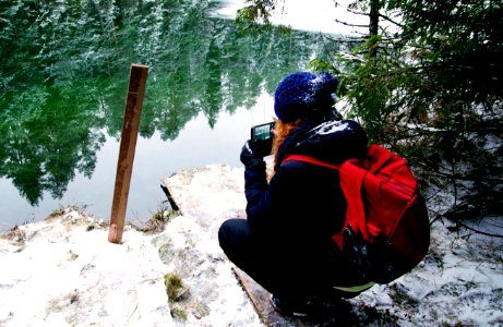 Person Carrying Red Backpack Capturing Photo Of Body Of Water