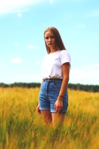 Woman Wearing White Crew-neck T-shirt Blue Denim Cuff Short Shorts While Standing On Grass Field photo